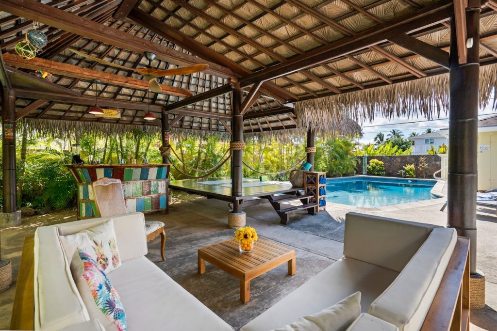 Tropical outdoor patio featuring a cabana, seating area, and swimming pool, perfect for luxury relaxation.